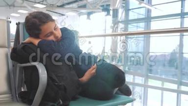 疲惫的少女少年旅行者睡在机场，等待飞机起飞，<strong>登机</strong>口的长椅上，她的行李都在她身边